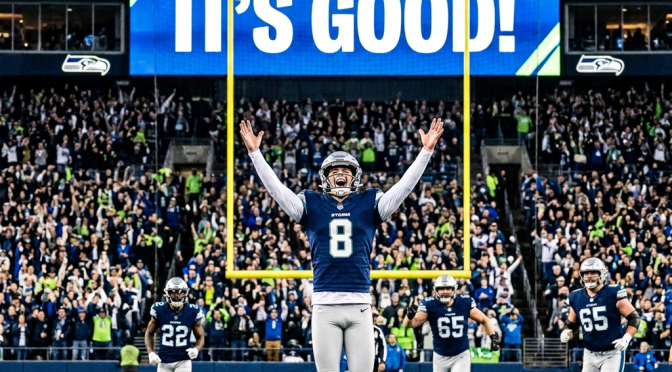 Seattle football player celebrating beneath goalposts with crowd behind him